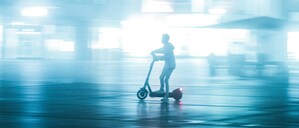 Eine Person fährt nachts auf einem E-Scooter durch die Stadt.
