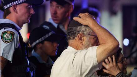 Ein Mitglied der jüdischen Gemeinde reagiert, als er am 14. Dezember 2025 mit der Polizei zum Tatort einer Schießerei am Bondi Beach in Sydney geht.