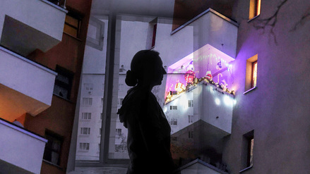 Die Illustration zeigt den Umriss einer Frau vor einer Wohnungsfassade. Sollten Normalverdiener eine Abgabe bezahlen, wenn sie in einer Sozialwohnung leben wollen?