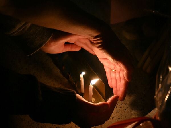 People light candles at the Bondi Pavillion in memory of the victims of a shooting at Bondi Beach, in Sydney on December 15, 2025. A father and son opened fire on a Jewish festival at Australia's Bondi Beach in a shooting spree that killed 15 people, including a child, authorities said on December 15, denouncing the attack as antisemitic "terrorism". (Photo by Saeed KHAN / AFP)