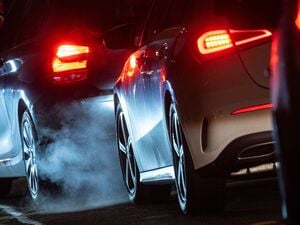 Autoabgase sind hinter einem Kraftfahrzeug im Straßenverkehr zu sehen.