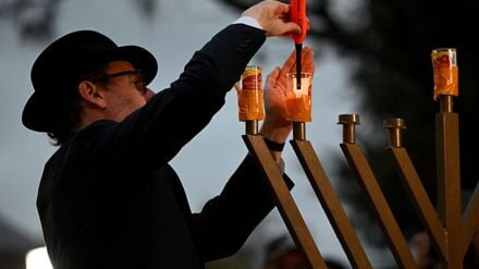 15.12.2025, Australien, Sydney: Ein Rabbi entzündet eine Menora während einer Mahnwache in Bondi Beach. Australien trauert, nachdem zwei bewaffnete Männer am Bondi Beach eine jüdische Feier angriffen und 15 Menschen töteten. Foto: Bianca De Marchi/AAP/dpa +++ dpa-Bildfunk +++