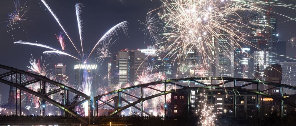 Mit Feuerwerk feiern Menschen vor der Bankenskyline in Frankfurt das neue Jahr.