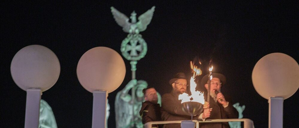Rabbiner Yehuda Teichtal (M.) und Kalman Meir Ber (r.), Oberrabiner des Staates Israel, zünden mit Fackeln die erste Kerze des Chanukka-Leuchters auf dem Pariser Platz vor dem Brandenburger Tor anlässlich der beginnenden Chanukka-Feiertage an.