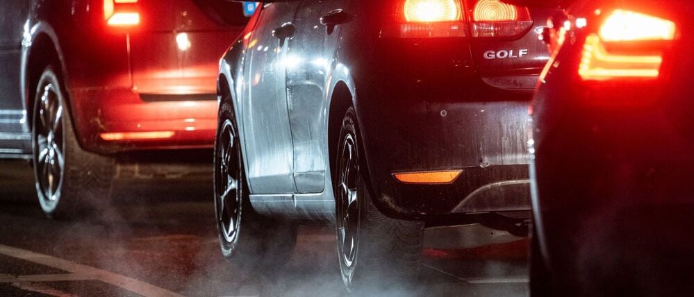 Autoabgase sind hinter einem Kraftfahrzeug im Straßenverkehr zu sehen.
