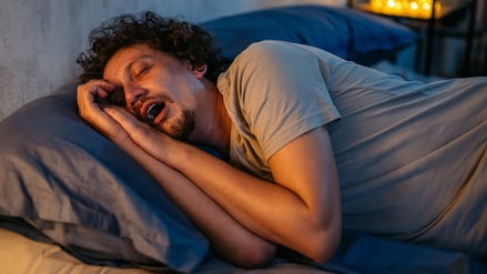 Ein mittelalter Mann schläft mit offenem Mund.