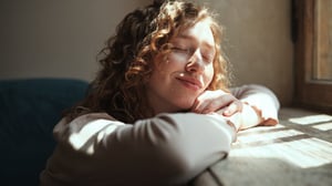 Eine junge Frau genießt Sonnenlicht, das durch ein Fenster fällt.