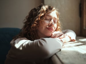 Eine junge Frau genießt Sonnenlicht, das durch ein Fenster fällt.