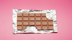 High angle view of chocolate bar on foil and pink background