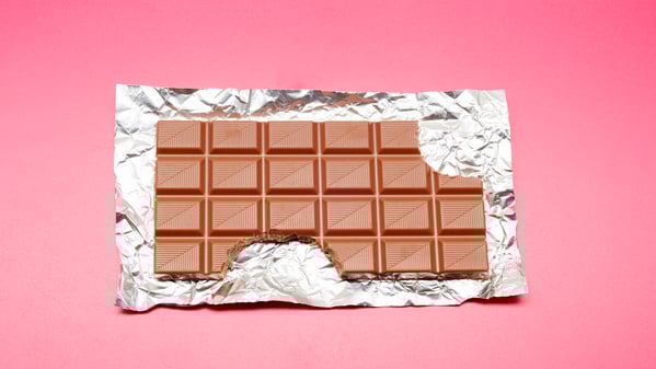 High angle view of chocolate bar on foil and pink background