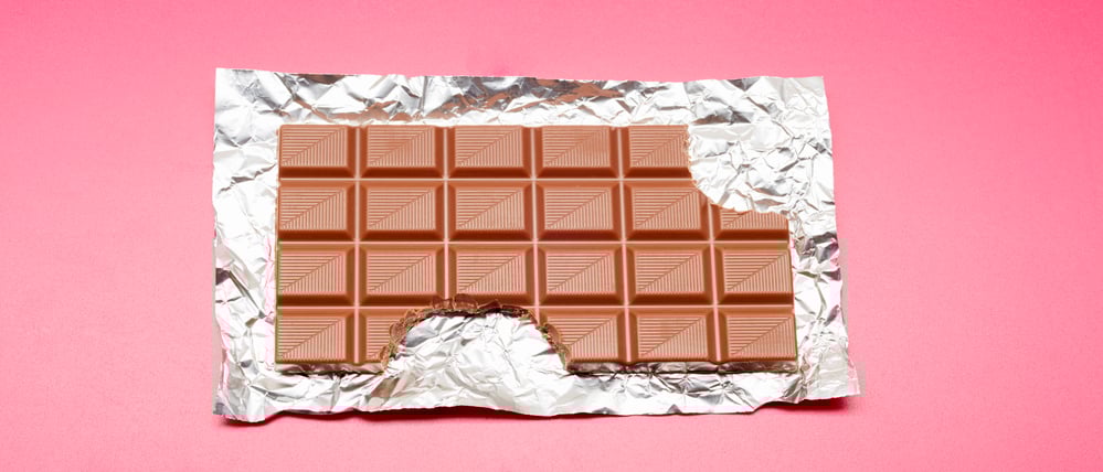 High angle view of chocolate bar on foil and pink background