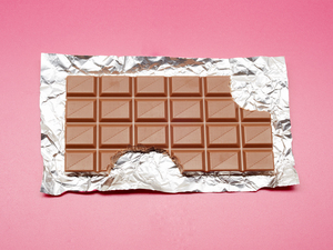 High angle view of chocolate bar on foil and pink background