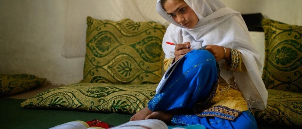 Die zehnjährige Hajira aus der afghanischen Provinz Nangarhar sitzt in einem Haus in einem abgelegenen Dorf östlich von Kabul über Schulbüchern und lernt. 