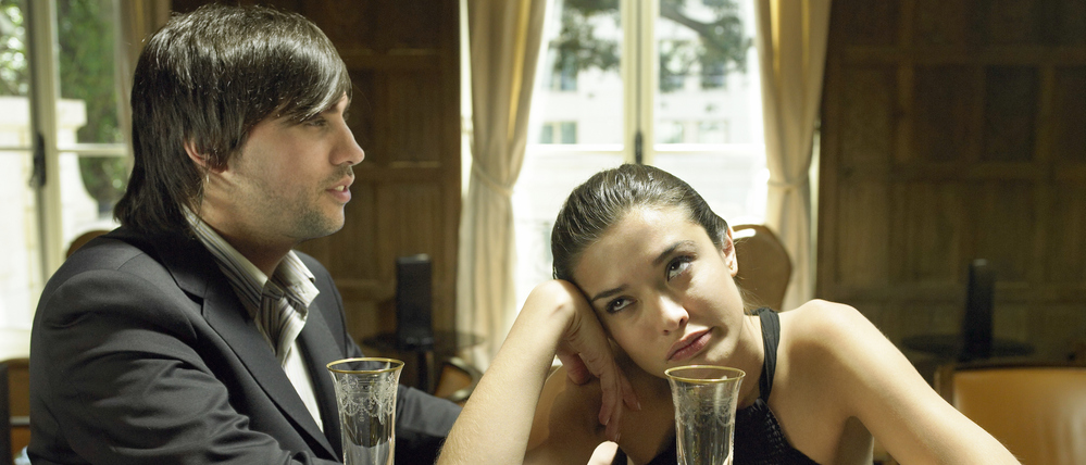 Ein gelangweilt wirkendes Paar mit leeren Sektgläsern (Symbolbild).