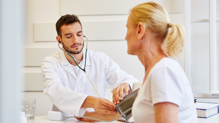 Arzt misst als Vorsorge den Blutdruck bei einer Patientin in seiner Praxis (Symbolbild)