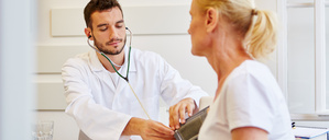 Arzt misst als Vorsorge den Blutdruck bei einer Patientin in seiner Praxis (Symbolbild)