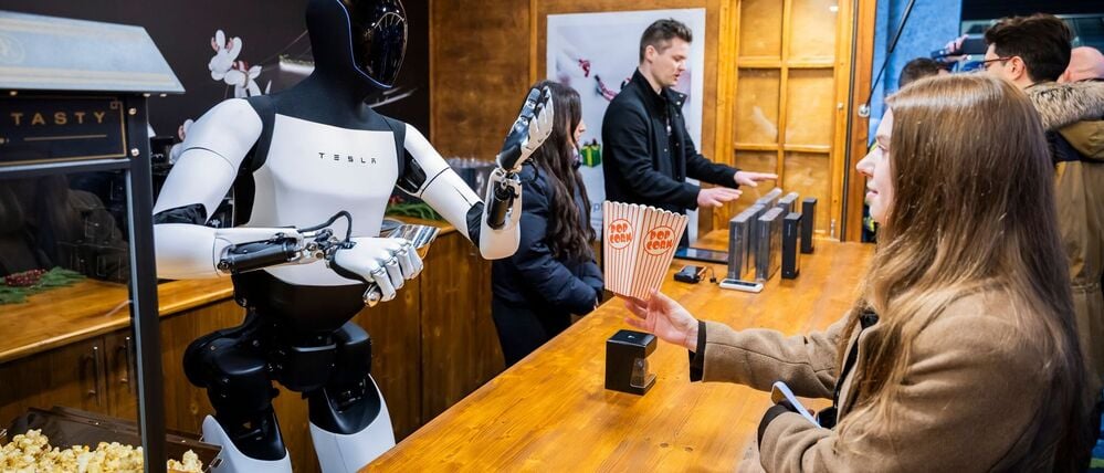 Der humanoide Roboter „Optimus“ von Tesla verteilt bei seiner Vorstellung in der Mall of Berlin Popcorn an eine Besucherin.