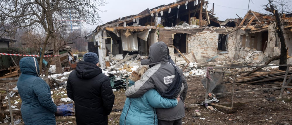 Eine ukrainische Familie vor ihrem zerstörten Haus.