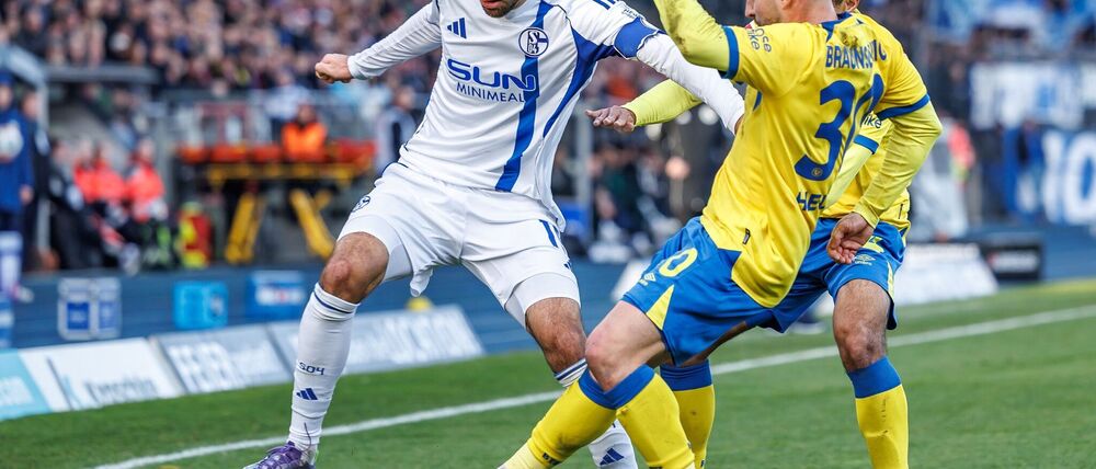 Die Braunschweiger Johan Gomez (verdeckt, Eintracht Braunschweig) und Robin Heußer bedrängen den Schalker Kenan Karaman (l).
