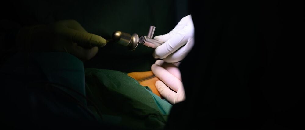 Ein Oberarzt führt in einem Operationssaal eine OP durch.