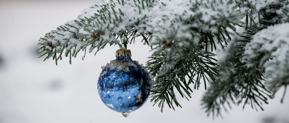 Bayern, Warmensteinach: An einem Nadelbaum hängt blauer Weihnachtsbaumschmuck. Die Wetterprognose für die Festtage ist noch unsicher.