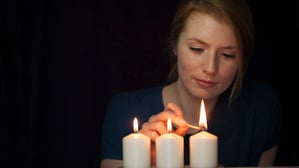Illustration: Eine Frau zündet drei Kerzen mit einem Streichholz an.
