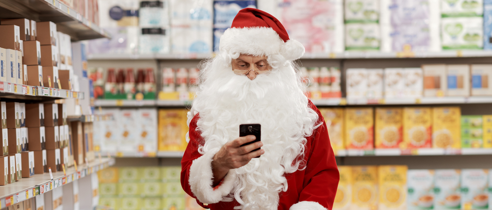 Ein Weihnachtsmann schiebt einen Einkaufswagen durch einen Supermarkt.