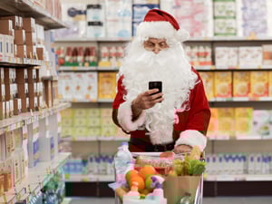 Ein Weihnachtsmann schiebt einen Einkaufswagen durch einen Supermarkt.