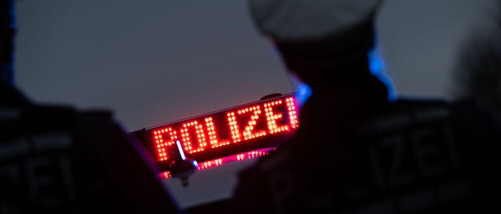 Zwei Polizisten stehen vor einem Schriftzug „Polizei“ (Symbolbild)
