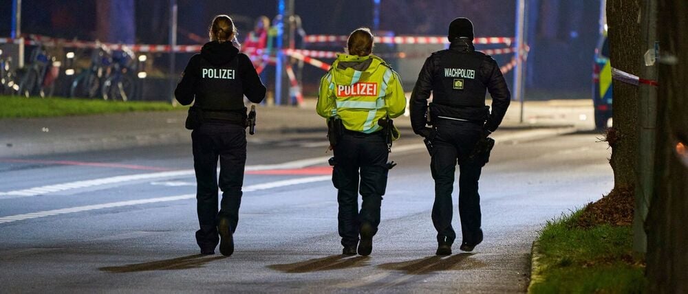 Polizeibeamte streifen durch den abgesperrten Bereich des Geschehens. 
