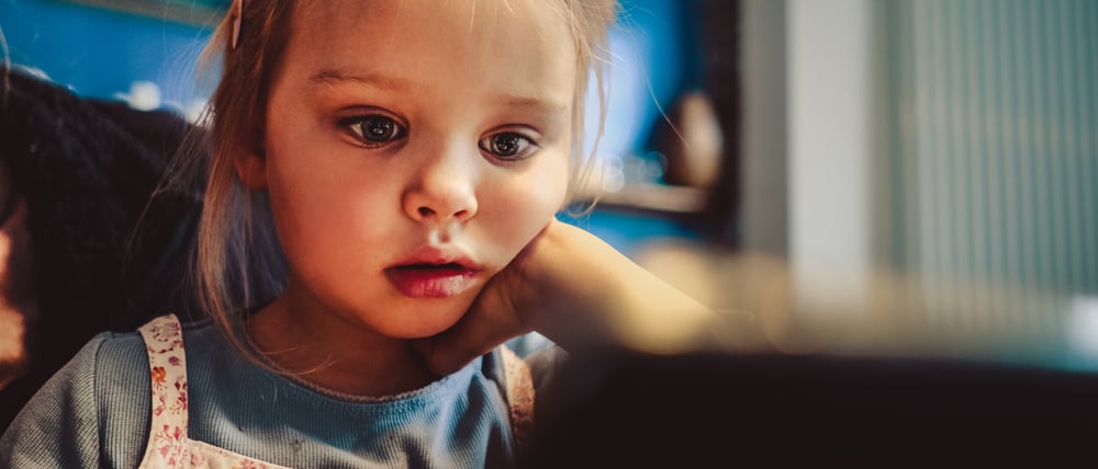Ein kleines Mädchen schaut auf einem Tablet Fernsehserien,