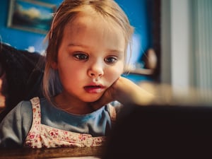 Ein kleines Mädchen schaut auf einem Tablet Fernsehserien,