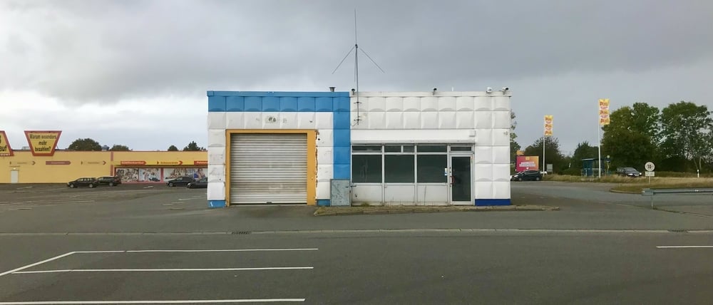 Ein leerer Parkplatz eines Supermarktes mit einer geschlossenen Autowerkstatt und trübem Himmel, aufgenommen in der Stadt Rendsburg in Schleswig-Holstein während der Corona-Pandemie im Oktober 2021.