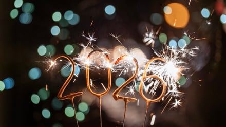 Sparklers form the numbers 2026, illuminating the night with bright sparks against a blurred, colorful bokeh background celebrating the New Year.