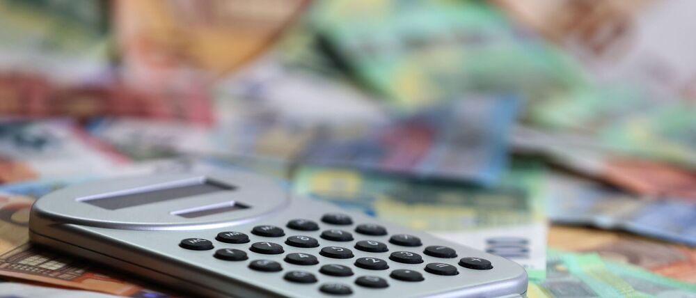 Ein Taschenrechner liegt auf verschiedenen Euro-Banknoten. (Symbolbild)