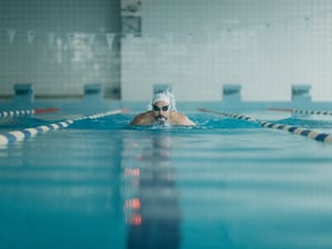 Ein Mann schwimmt Bahnen in einer Schwimmhalle. (Symbolbild)