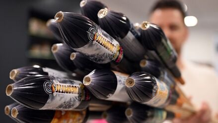 Ein Mitarbeiter hält im Showroom der Feuerwerksfirma Weco Silvesterraketen.