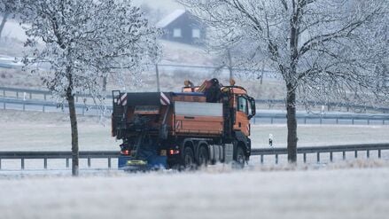 Ein Streu- und Räumfahrzeug des Winterdienstes fährt bei Böttingen (Landkreis Tuttlingen) während leichten Schneefalls auf einer Straße.