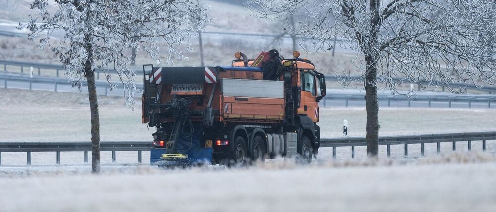 Ein Streu- und Räumfahrzeug des Winterdienstes fährt bei Böttingen (Landkreis Tuttlingen) während leichten Schneefalls auf einer Straße.