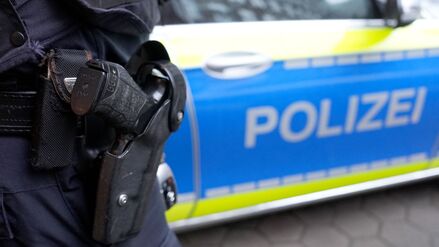 ARCHIV - 15.03.2024, Hamburg: Ein Polizist mit Schusswaffe steht vor einem Einsatzfahrzeug der Polizei. (Symbolbild) (zu dpa: «Polizei erschießt Mann bei Einsatz in Gießener Klinik») Foto: Marcus Brandt/dpa +++ dpa-Bildfunk +++