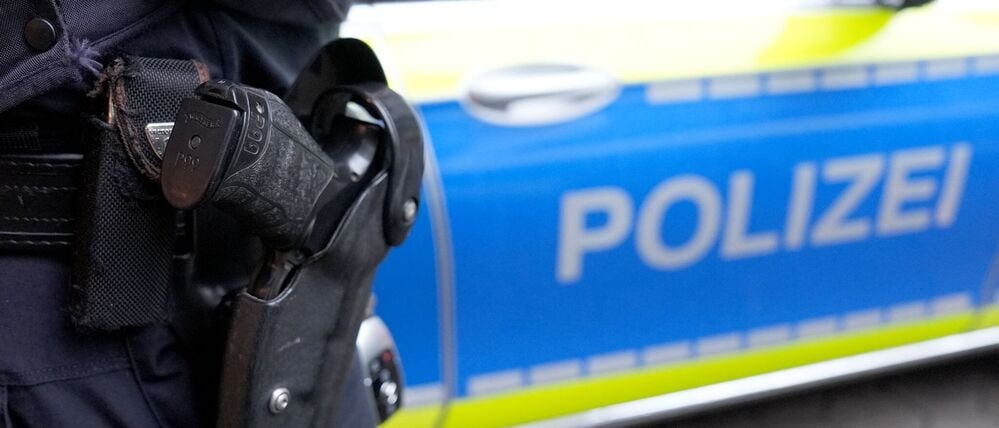 ARCHIV - 15.03.2024, Hamburg: Ein Polizist mit Schusswaffe steht vor einem Einsatzfahrzeug der Polizei. (Symbolbild) (zu dpa: «Polizei erschießt Mann bei Einsatz in Gießener Klinik») Foto: Marcus Brandt/dpa +++ dpa-Bildfunk +++