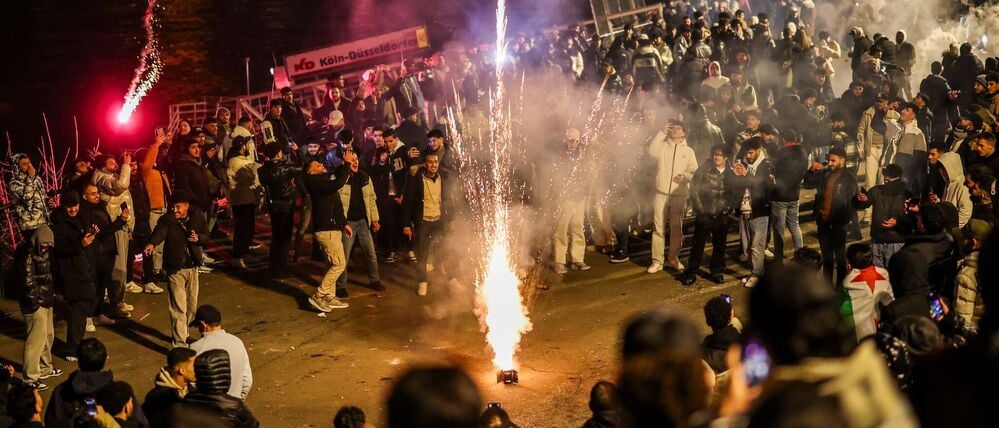 Männer zünden an Silvester in der Böllerbotszone in der Düsseldorfer Altstadt Feuerwerk.