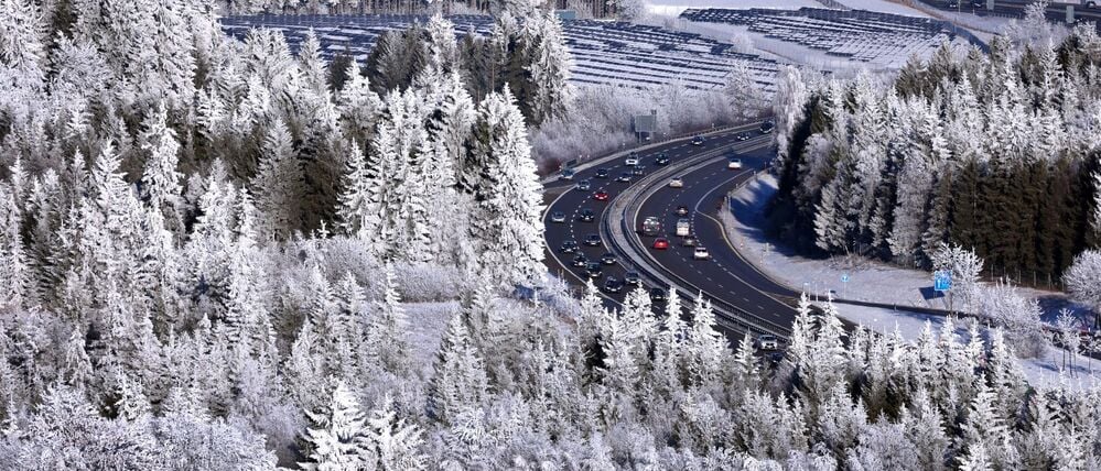 Autos fahren auf der in der winterlichen Landschaft gelegenen Autobahn 7 bei Oy-Mittelberg in Bayern.