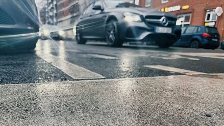 Das Licht der Fahrzeuge an einer Ampel bricht sich im Asphalt einer Straße. Blitzeis verwandelte besonders die Gehwege in Rutschbahnen.