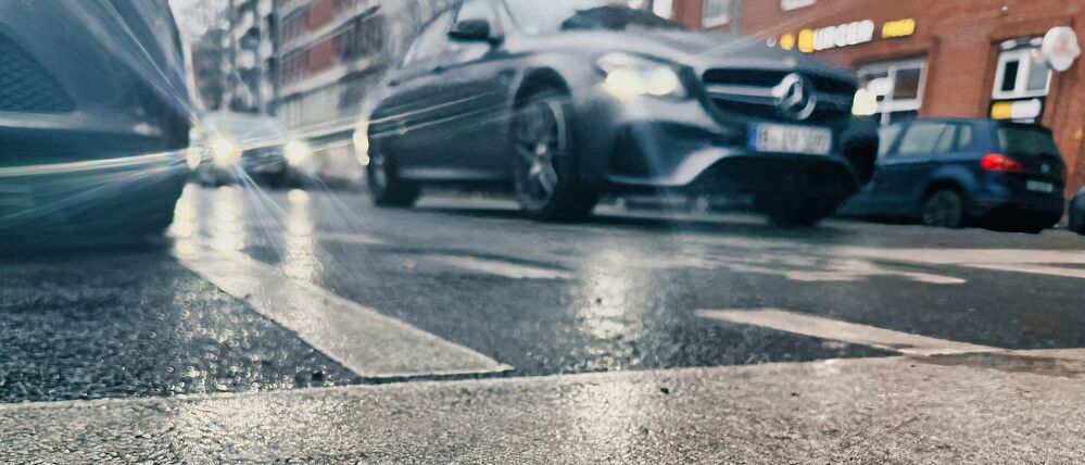 Das Licht der Fahrzeuge an einer Ampel bricht sich im Asphalt einer Straße. Blitzeis verwandelte besonders die Gehwege in Rutschbahnen.
