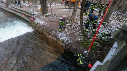 Mitarbeiter der Berufsfeuerwehr bauen in Anwesenheit von Polizeibeamten die diversen Einbauten und Vorrichtungen für eine künstliche Welle am Eisbach wieder ab.