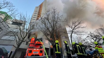 Einsatzfahrzeuge von Rettungskräften und Feuerwehr stehen vor einem Hochhaus, aus dem Rauch aufsteigt. In Berlin-Spandau brennt seit den frühen Morgenstunden ein Hochhaus. 