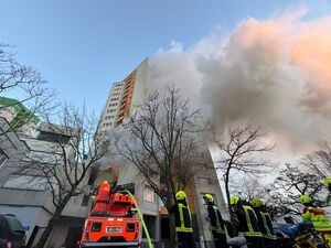 Einsatzfahrzeuge von Rettungskräften und Feuerwehr stehen vor einem Hochhaus, aus dem Rauch aufsteigt. In Berlin-Spandau brennt seit den frühen Morgenstunden ein Hochhaus. 