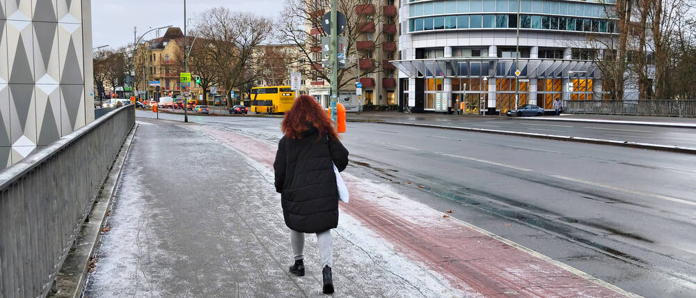Eine Person läuft vorsichtig auf der Halenseebrücke Kurfürstendamm
