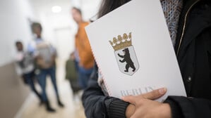 Eine Frau hält im Bürgeramt im Landesamt für Einwanderung (LEA) ihre Einbürgerungsurkunde in der Hand.